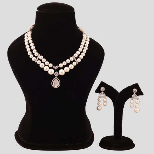 Pearl necklace and earrings set on a black mannequin and stand against a gray background