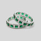Pair of emerald and diamond eternity rings on a light gray background