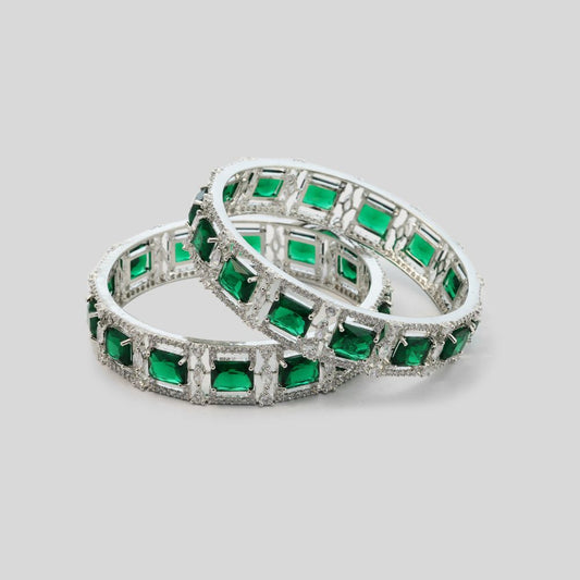 Pair of emerald and diamond eternity rings on a light gray background