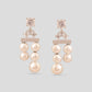 Pair of pearl earrings with rose gold accents on a light gray background
