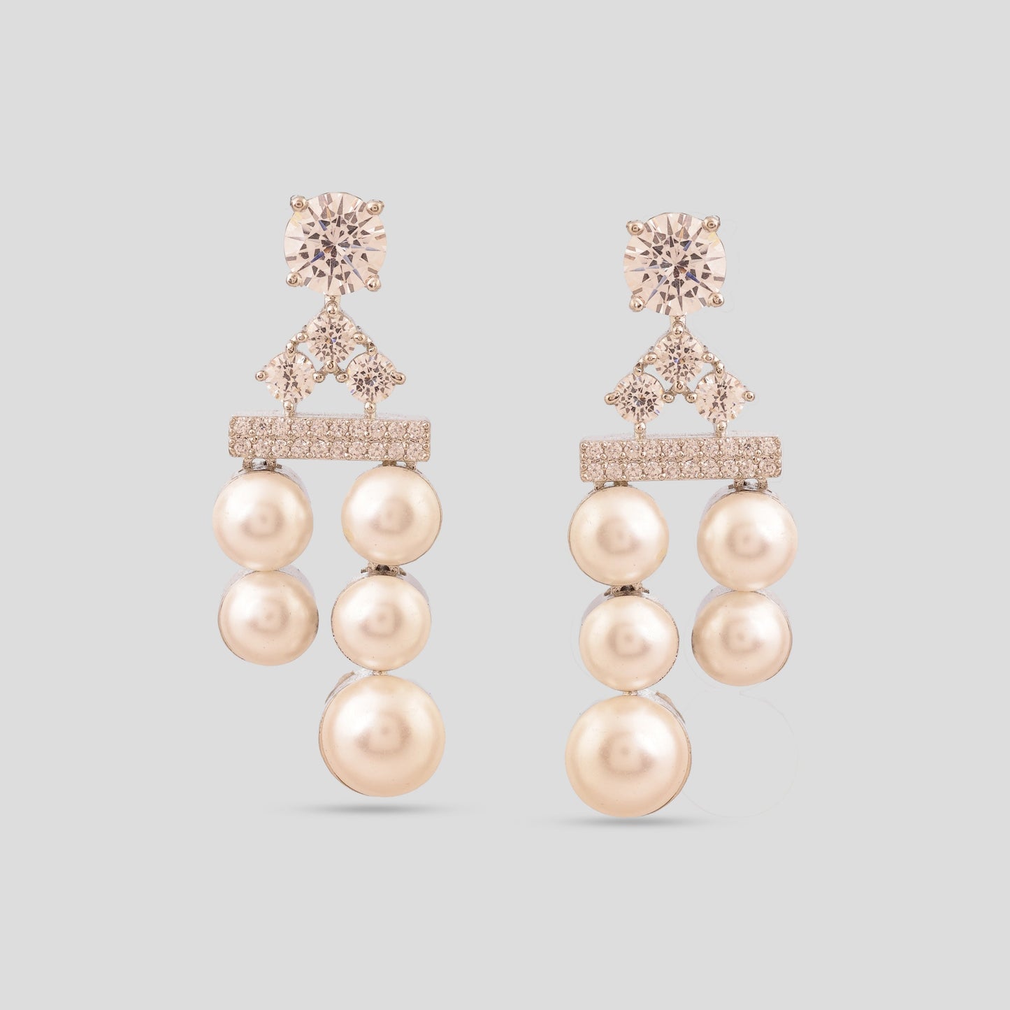 Pair of pearl earrings with rose gold accents on a light gray background