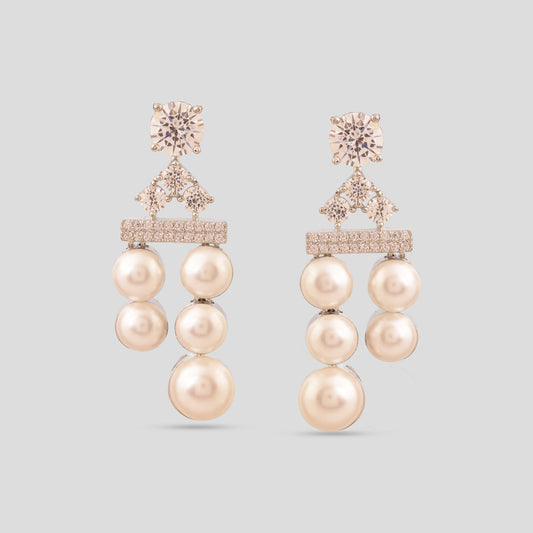 Pair of pearl earrings with rose gold accents on a light gray background
